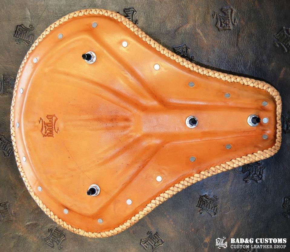 "CROSS" design hand tooled and braided on a chopper solo seat. Brown Veg tan leather with kangaroo lace.