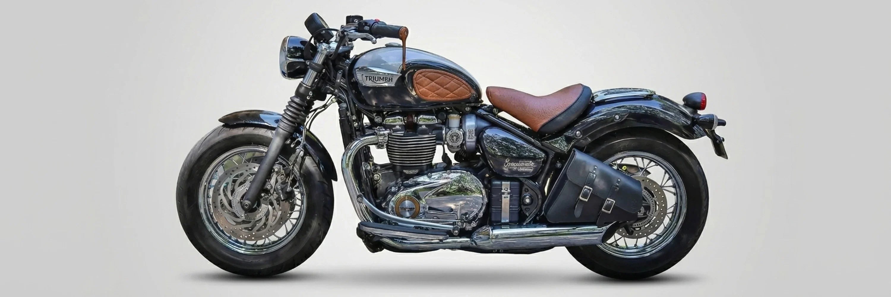 Triumph Bobber motorcycle with a BAD&G left-side black leather solo bag and brown leather seat.