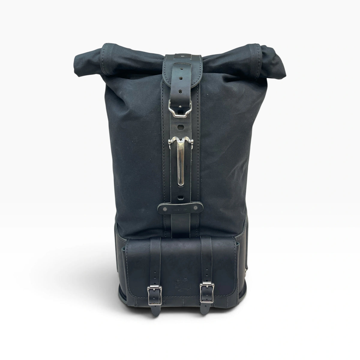 A black roll-top backpack made of durable canvas and leather, featuring silver metal buckles and a vertical strap closure, shown against a plain white background.